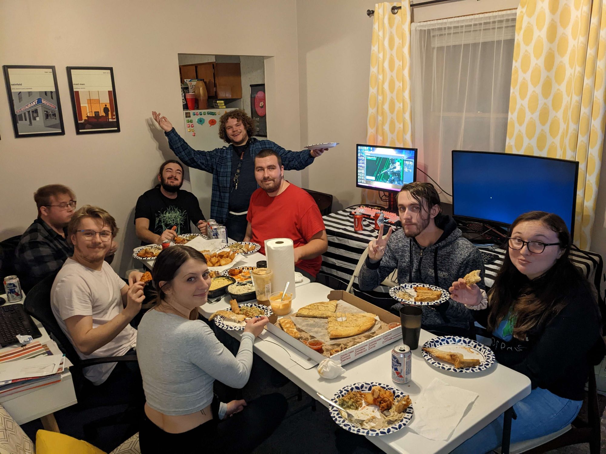 Guests around a table of pizza, wings and garlic bread at a past LAN party
